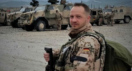 Dhany Sahm in Uniform in Afghanistan, im Hintergrund Autos der Bundeswehr in Tarnfarben